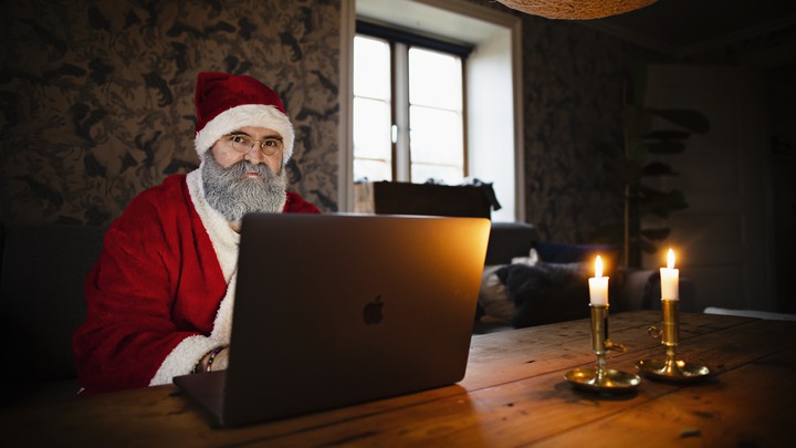 Tomten Tobias Guldstrand har sprayat skägget vitt och sitter redo vid datorn.