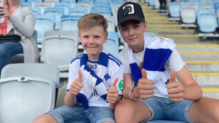 Tim och Vilgot sitter p&aring; l&auml;ktaren vid en fotbollsmatch.