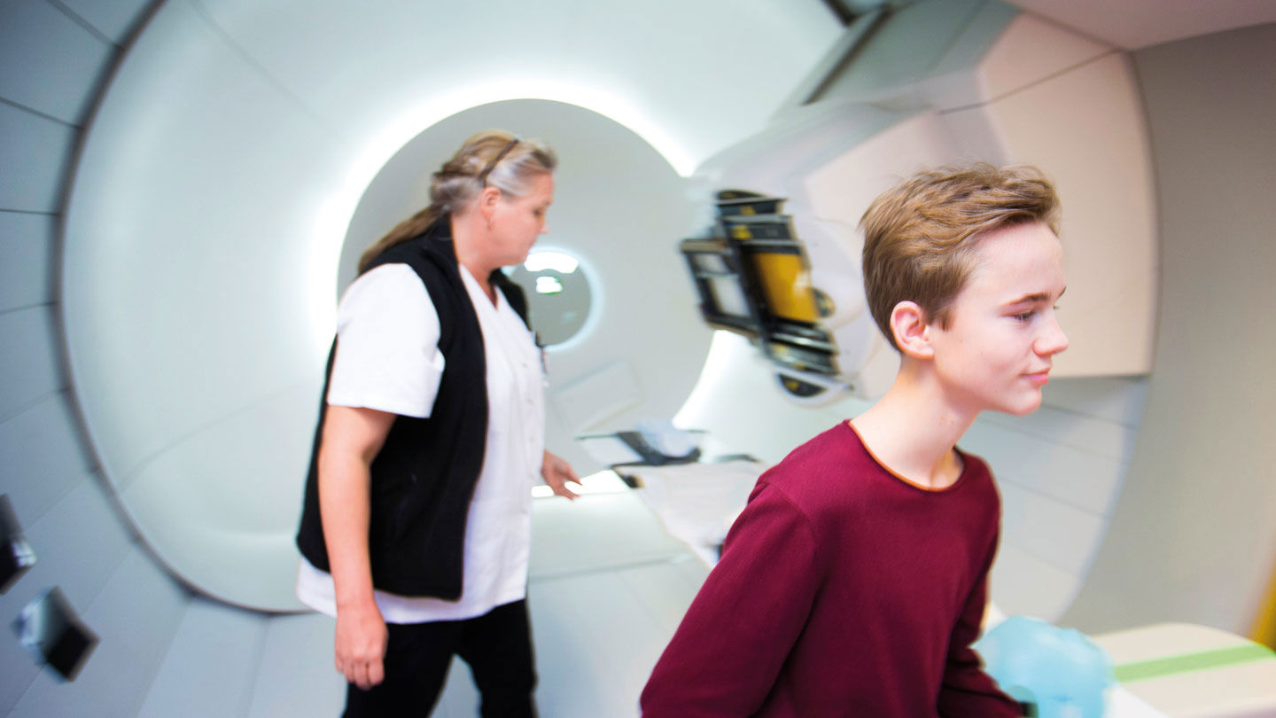 Joel står framför strålningsmaskinen på sjukhuset.