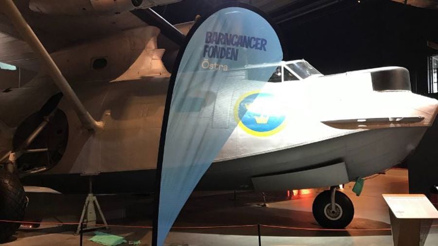 Flagga med BCF Östra logga framför gammalt flygplan