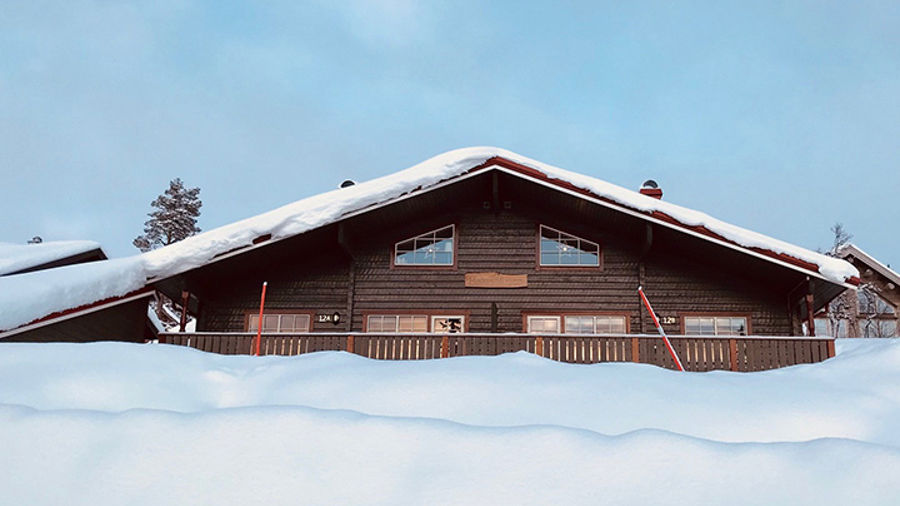 Gråmålad fjällstuga inbäddad i snö