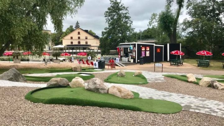Minigolfbana med parasoller och utemöbler i bakgrunden
