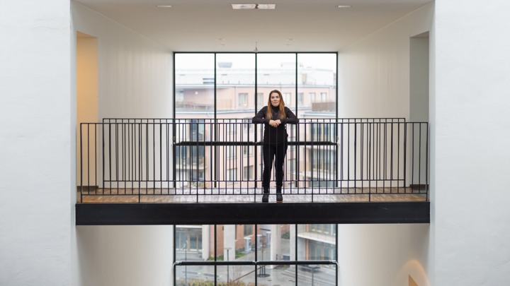 En kvinna st&aring;r p&aring; en balkong bredvid ett f&ouml;nster